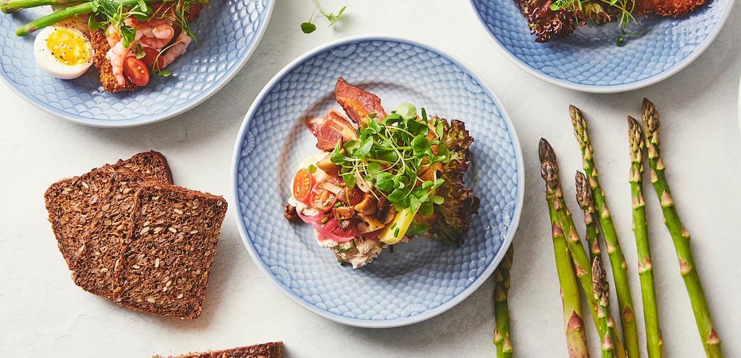 Smørrebrød fra den bette kro, omringet af rugbrød og asparges