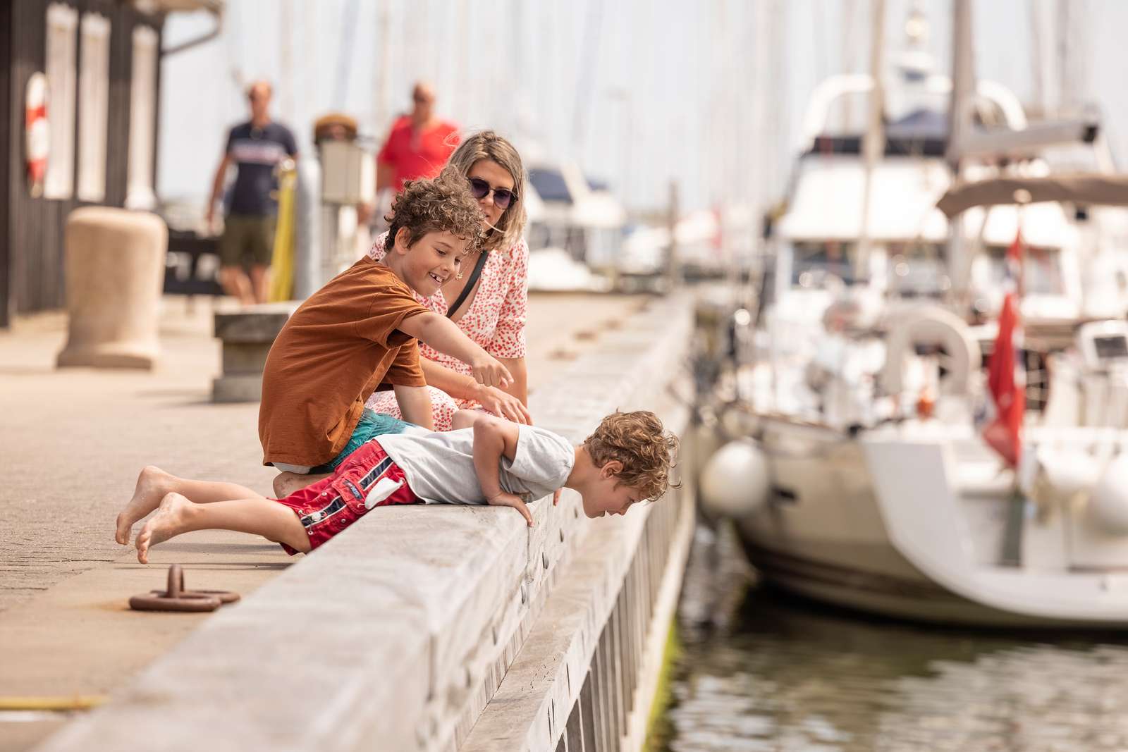 Tre mennesker som kigger ned på vandet i havnen