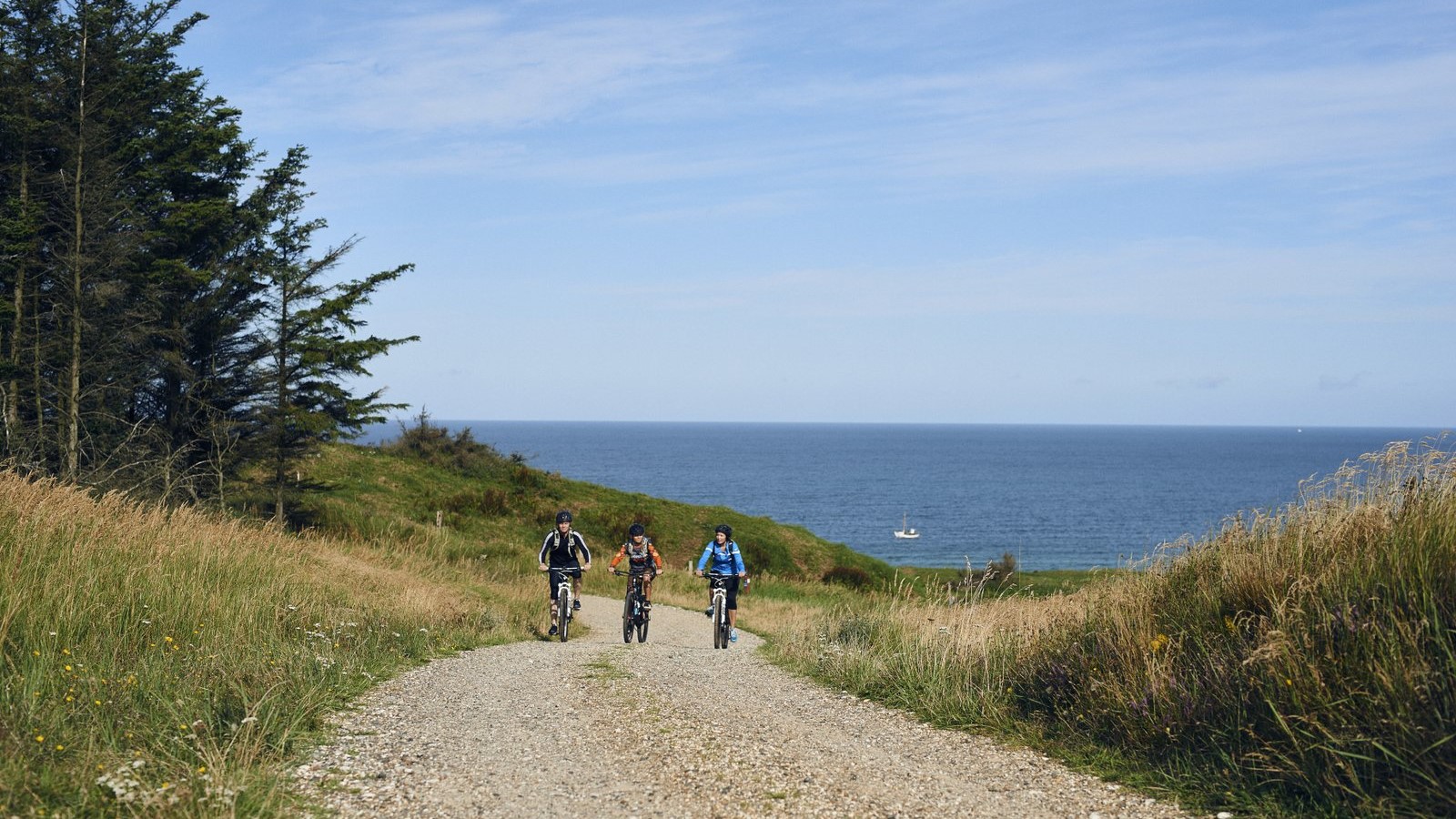 Tre mennesker der cykler i bakker